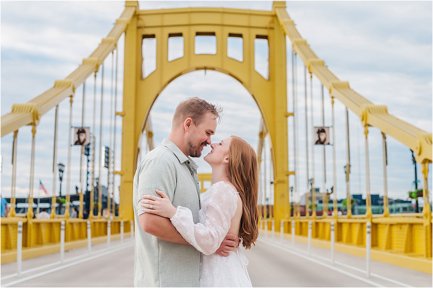 couple standing in the middle of the roberto clemente bridge for engagement photos • Incredible Pittsburgh Yellow Bridges Engagement Photos