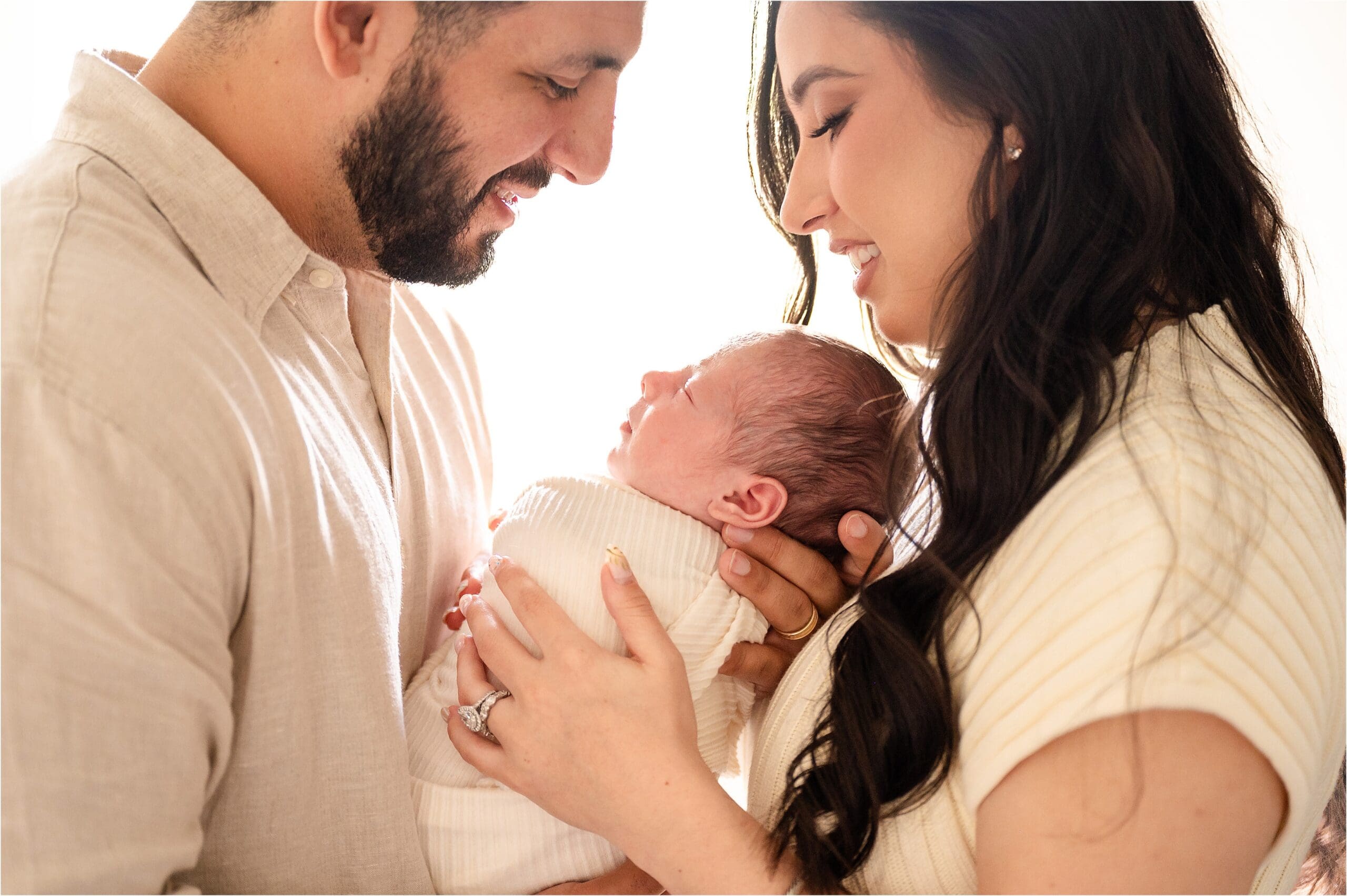 backlit photo with warm tones of parents looking at baby
